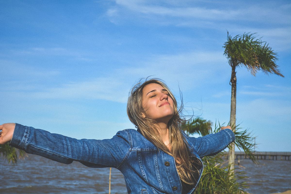 woman spreading arms near body of water